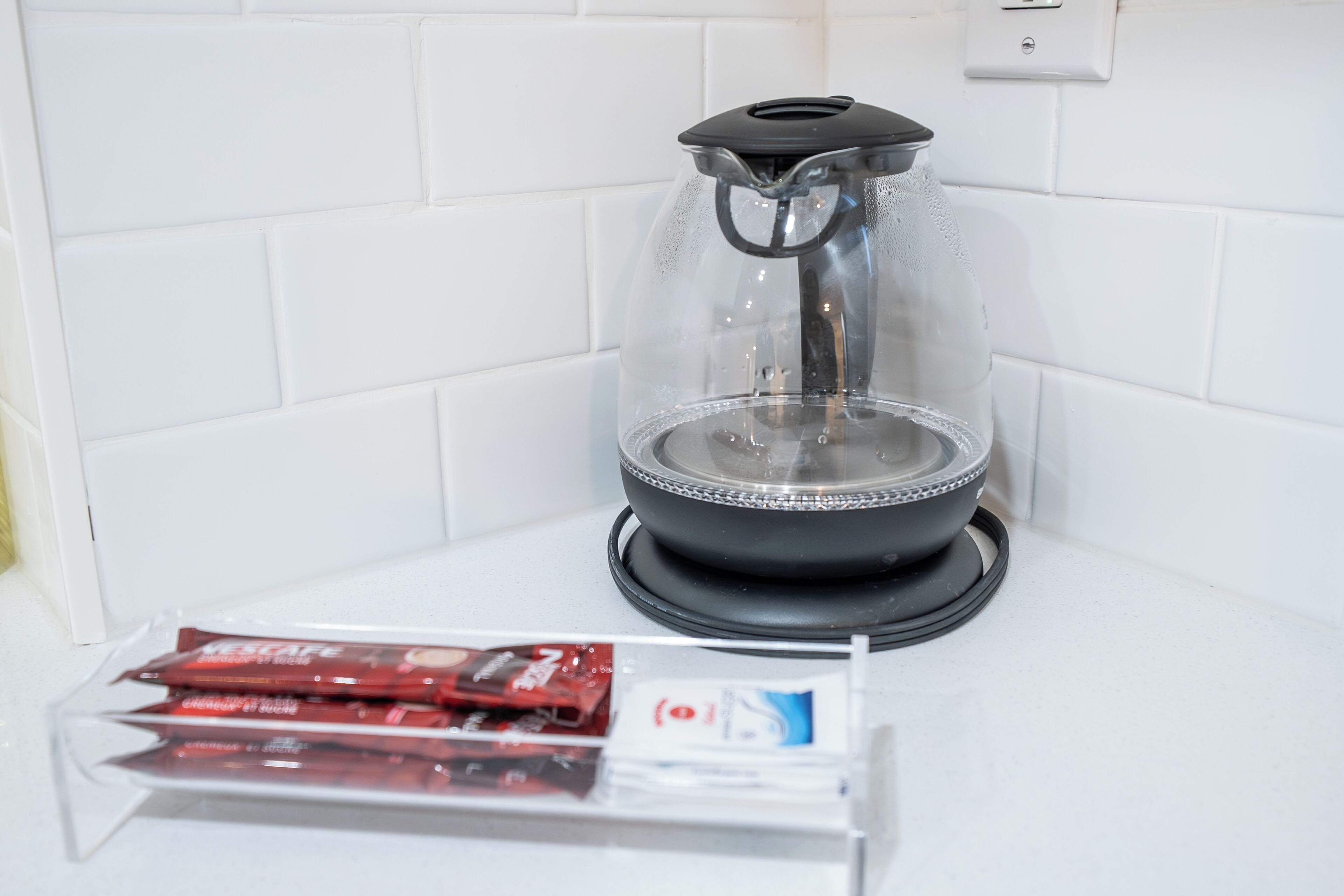 A coffee maker with a transparent water container and a black base, placed on a white countertop.
