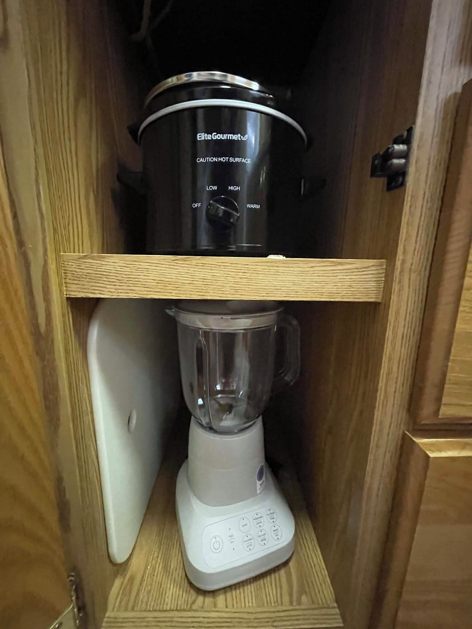 Una cocina con una licuadora y una olla de cocción lenta en un estante.