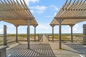 Una passerella di legno che conduce alla spiaggia sotto un cielo sereno.