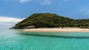 A beach with clear turquoise water and a hill with dense greenery. - 2-br Countryside Apartment in Mouzaki (Zakynthos)