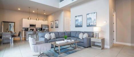 A spacious living area with a sofa, coffee table, and a dining area with chairs.