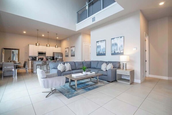 A spacious living area with a sofa, coffee table, and a dining area with chairs. - Premium Location Spectrum at Reunion Near Disney (Kissimmee)