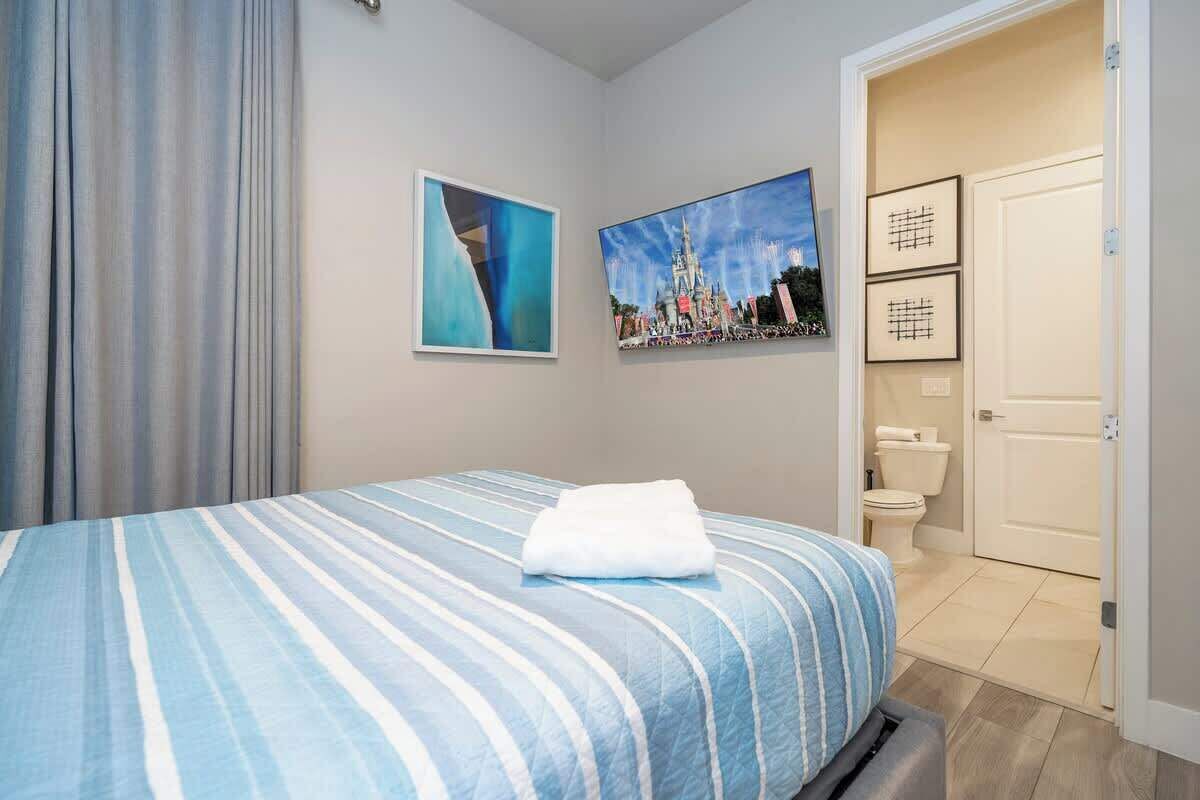 A hotel room with a bed, a bathroom, and two framed pictures on the wall.