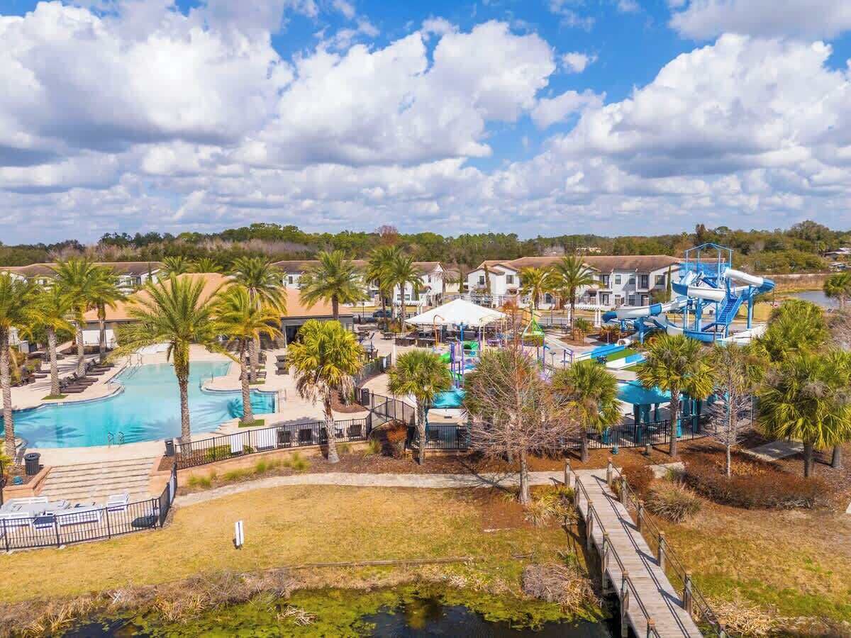 Een resort met meerdere zwembaden, palmbomen en een glijbaan.