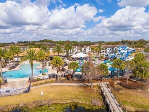 Ein Resort mit mehreren Swimmingpools, Palmen und einer Wasserrutsche.