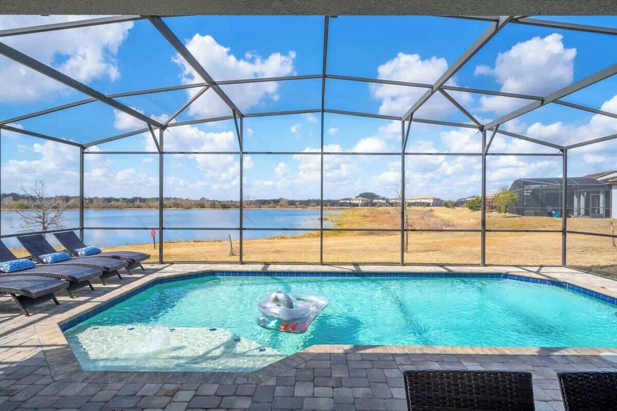 Una piscina techada con vista a un lago y edificios al fondo.