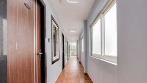 A long, narrow hallway with wooden flooring and large windows on one side. - Hotel O Kotipalli (Rajahmundry)