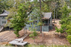 A cabin with a deck and outdoor seating, surrounded by trees and a dirt path. - The Night Owl at Lake Martin - 3BR/3BA Home in Eclectic (Eclectic)