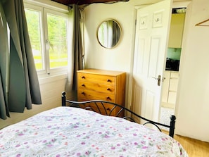 A bedroom with a bed, a dresser, a mirror, and a window with curtains. - Cosy cabin, w/modern comforts minutes away from popular beaches & seaside towns. (Old Romney)