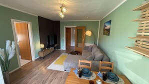 Ett modernt vardagsrum med en soffa, ett matbord och en tv-apparat i bakgrunden.