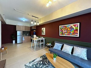 Ein modernes Wohnzimmer mit einer Couch, einem Esstisch und einer Küche im Hintergrund.