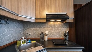 Una cucina moderna con mobili in legno, lavello in acciaio inox e piano di lavoro nero.