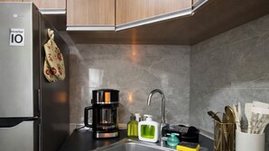 A modern kitchen with a stainless steel refrigerator, a coffee maker, a sink, and a utensil holder. - Noirwood Studio | IT Park Pool + Fast WiFi (Cebu City)