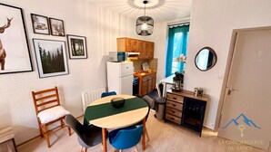 Una cocina compacta con refrigerador, microondas y un pequeño comedor con mesa y sillas.