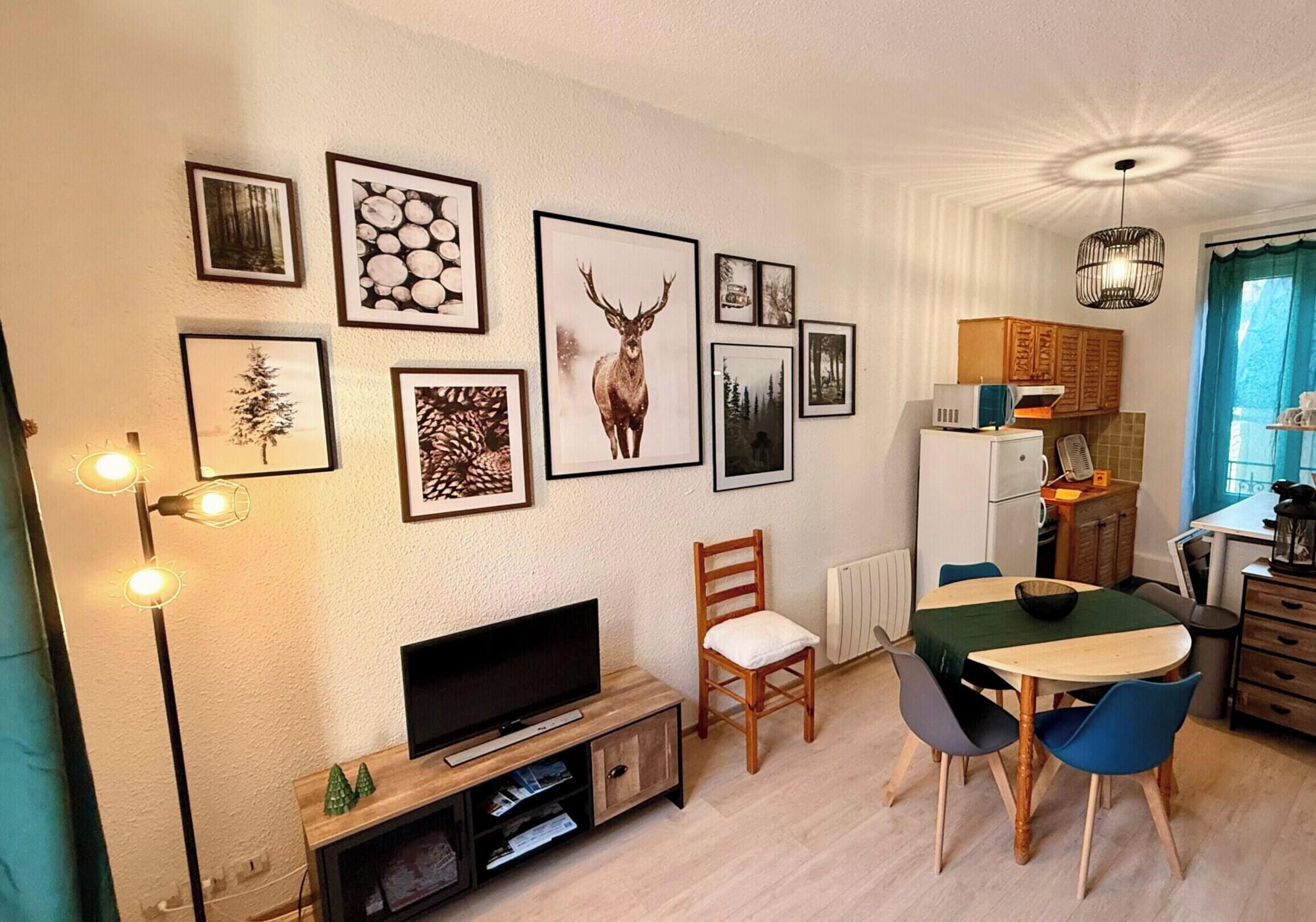 Un salon comprenant un téléviseur, une table à manger, des chaises et des tableaux encadrés accrochés au mur.