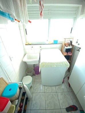 A compact kitchen with a sink, a window, and a small countertop. - Apartment 68m² | 3 bedrooms (1 suite) | Furnished | 2 parking spaces | Balcony and service area (São Paulo)