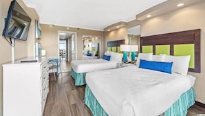 A hotel room with two beds, a desk, a TV, and a bathroom visible through an open door. - Relaxing 1 bedroom oceanfront. (Myrtle Beach)