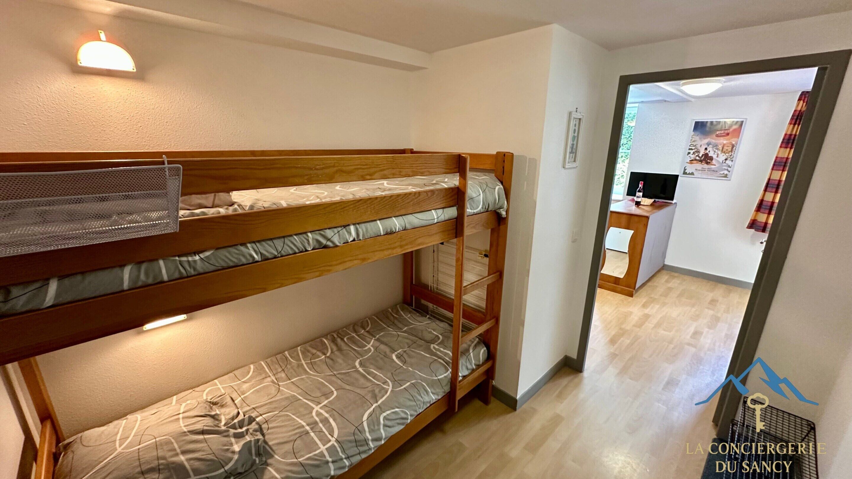 Une chambre avec un lit superposé, un bureau et un téléviseur.
