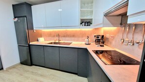 A modern kitchen with grey cabinets, a built-in oven, a sink, and a countertop with a kettle and coffee maker. - old town experience like no other (Gibraltar)