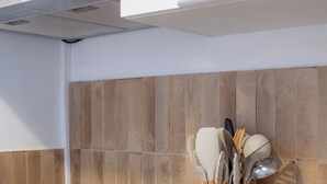 Una cocina con encimera de madera, electrodoméstico blanco y un portalapices.