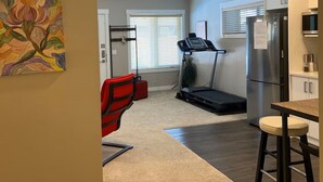 A compact kitchen with a treadmill, a refrigerator, and a dining area. - Family friendly, super clean & Cozy Walkout basement suite with all amentities (Calgary)