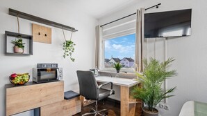 Un petit espace de bureau comprenant un bureau, une chaise et un four à micro-ondes.