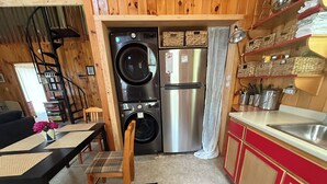 Een compacte keuken met een wasmachine, een koelkast en een eethoek met een tafel en stoelen.