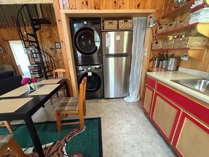 Een compacte keuken met een wasmachine, een koelkast en een eethoek met een tafel en stoelen.