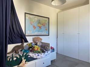 A child's bedroom with a bed, a world map, and a wardrobe. - Family home in Assas (Assas)