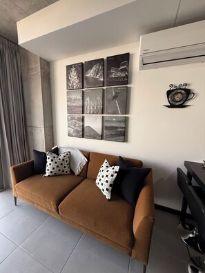Uma sala de estar moderna com um sofá marrom, uma mesa de centro e uma exposição de fotografias preto e branco na parede.