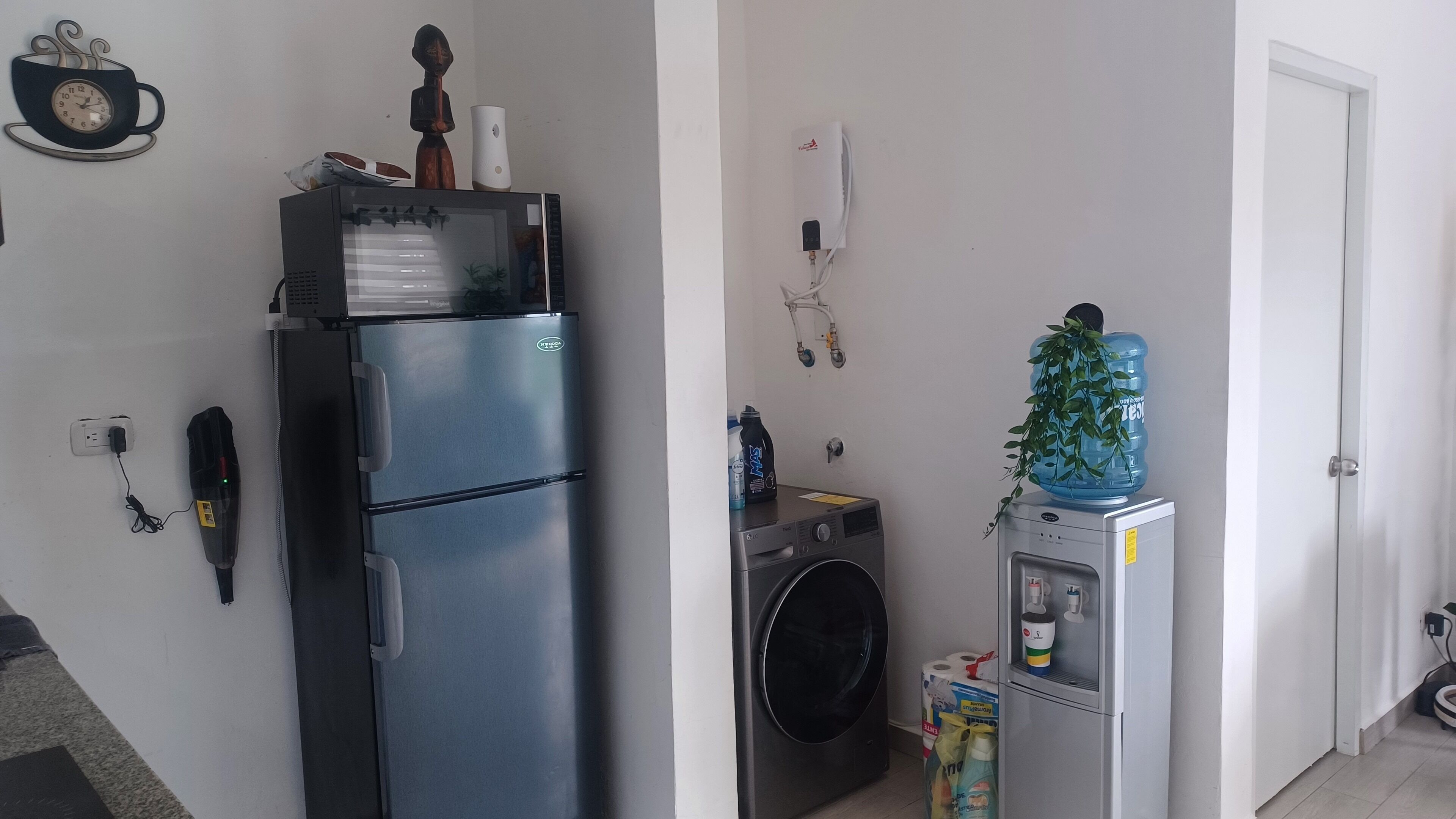 Eine kompakte Küche mit einem Edelstahl-Kühlschrank, einer Waschmaschine und einem Wasserspender.