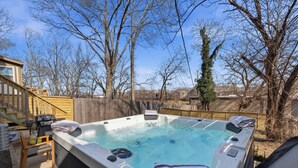 Un bain à remous avec une terrasse en bois, une chaise et une serviette.