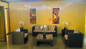 A lobby with a sofa, two armchairs, a coffee table, and two potted plants.