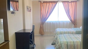 A bedroom with a bed, a desk, a chair, and a television.
