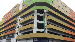 A multi-story parking garage with a green and white facade, multiple levels, and a sign for "Universal Repuestos."