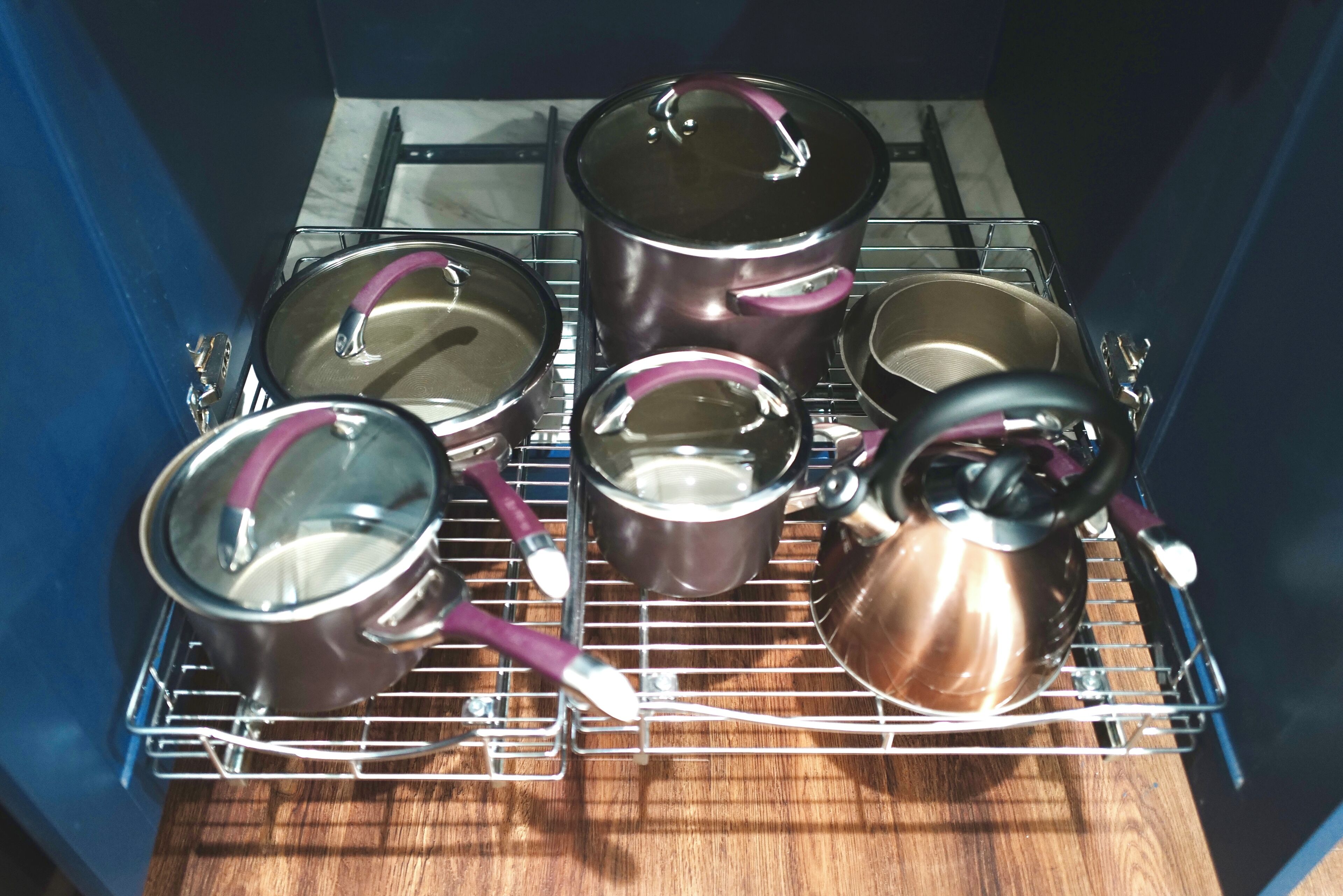 A kitchen with a rack holding pots and pans.