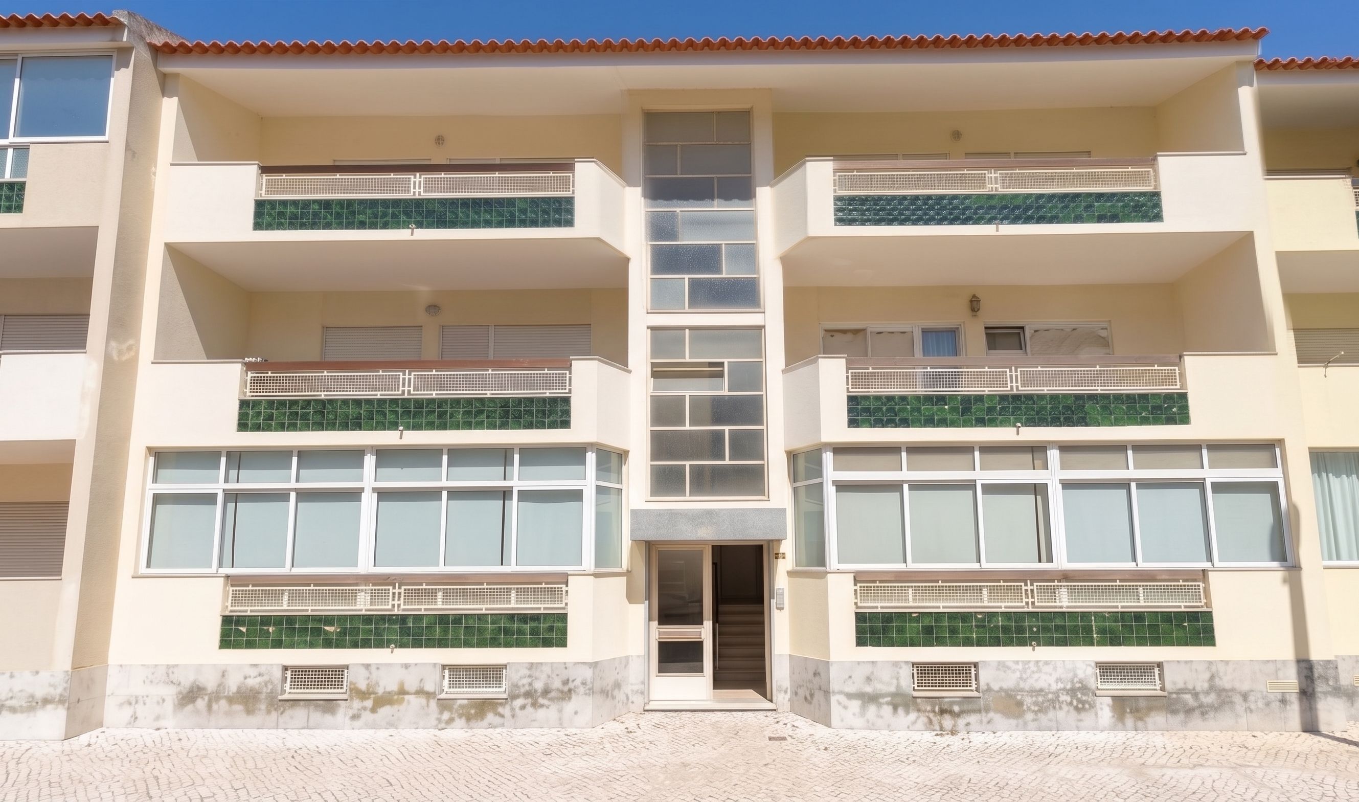 A multi-story building with balconies, large windows, and a tiled facade.