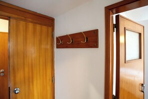 A wooden door with a handle, a wall-mounted hookboard, and a frosted glass panel. - Central Cascais 1BDR With Balcony Near The Beach (Cascais)