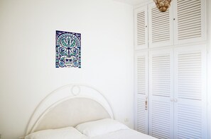 A bedroom with a white bed, a wall hanging, and white louvered closets. - Magnificent seaside residence with a 50 m² rooftop terrace and 2 large balconies (Villanova)