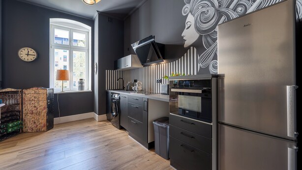 Eine moderne Küche mit Einbauofen, Edelstahlkühlschrank und großem Fenster mit Blick auf Gebäude.