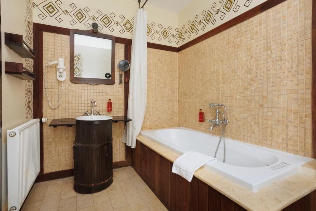 A bathroom with a bathtub, a sink, a mirror, and a toilet.
