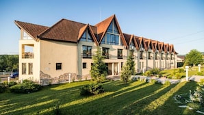A modern hotel with a symmetrical facade, multiple balconies, and a well-maintained lawn.