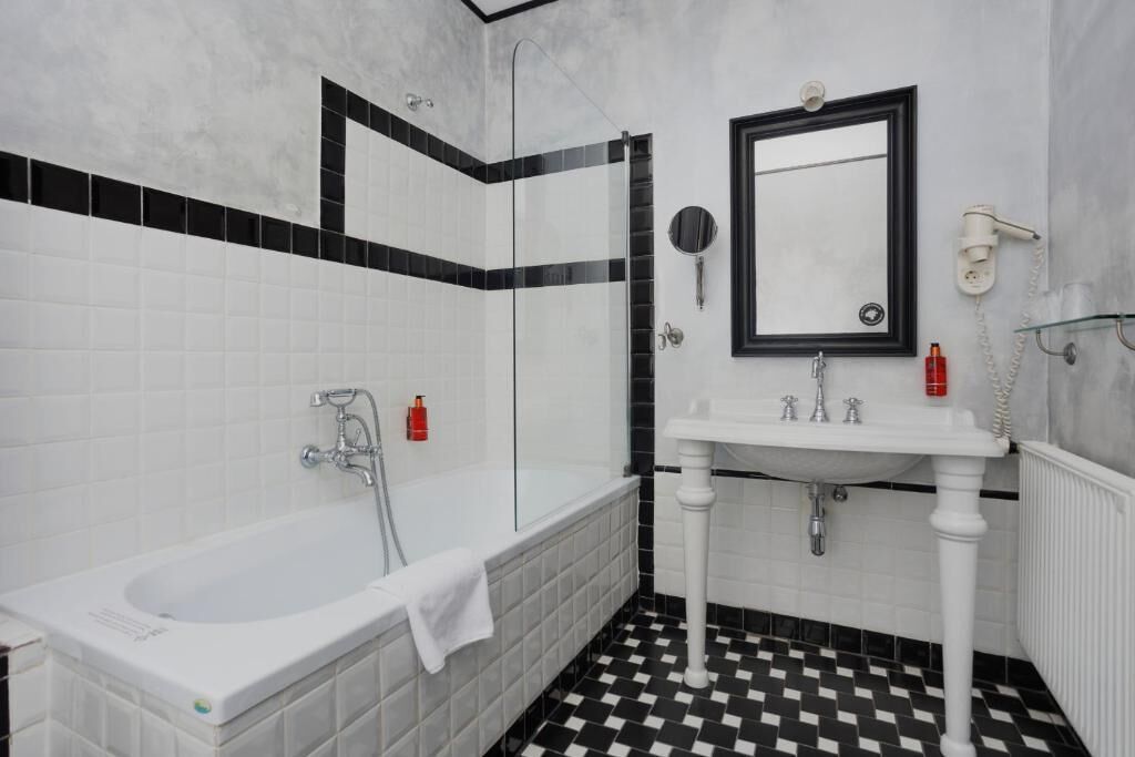 A bathroom with a bathtub, a sink, and a mirror.