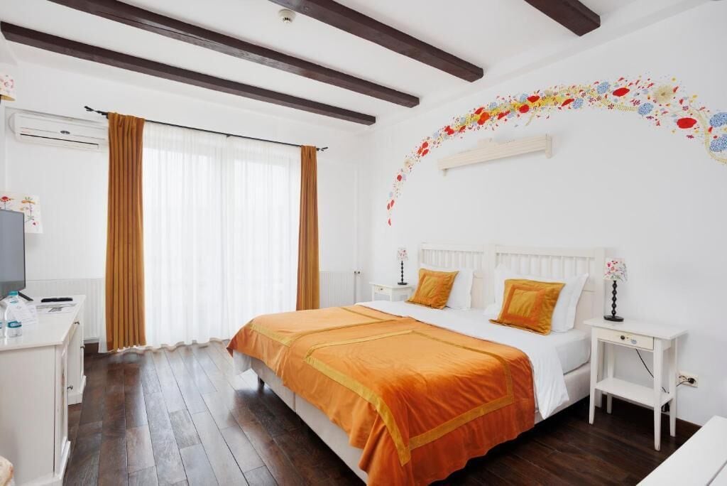 A bedroom with a large bed, white headboard, and a decorative wall arch.