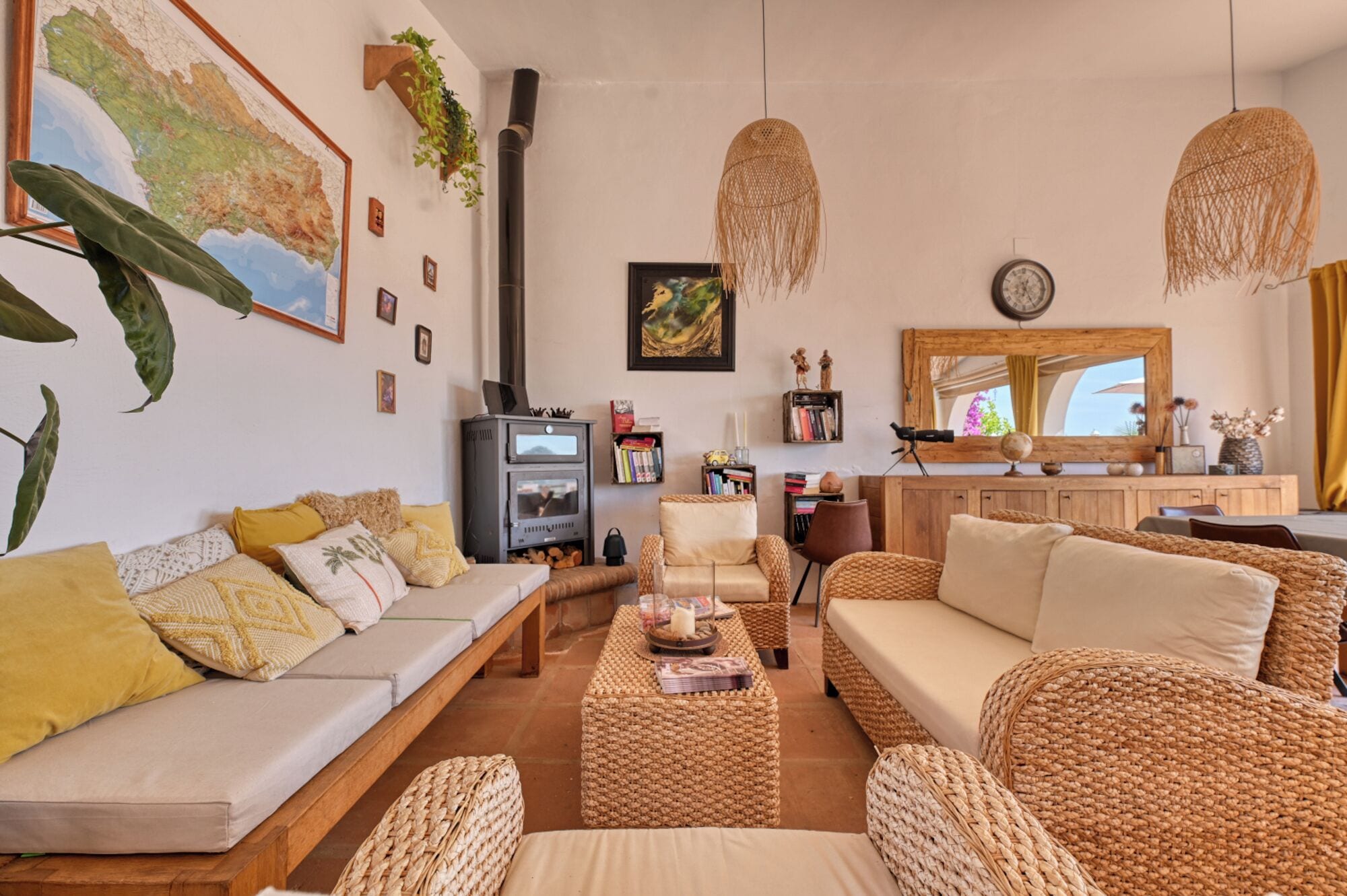A cozy living room with a sofa, wicker furniture, a fireplace, and a bookshelf.