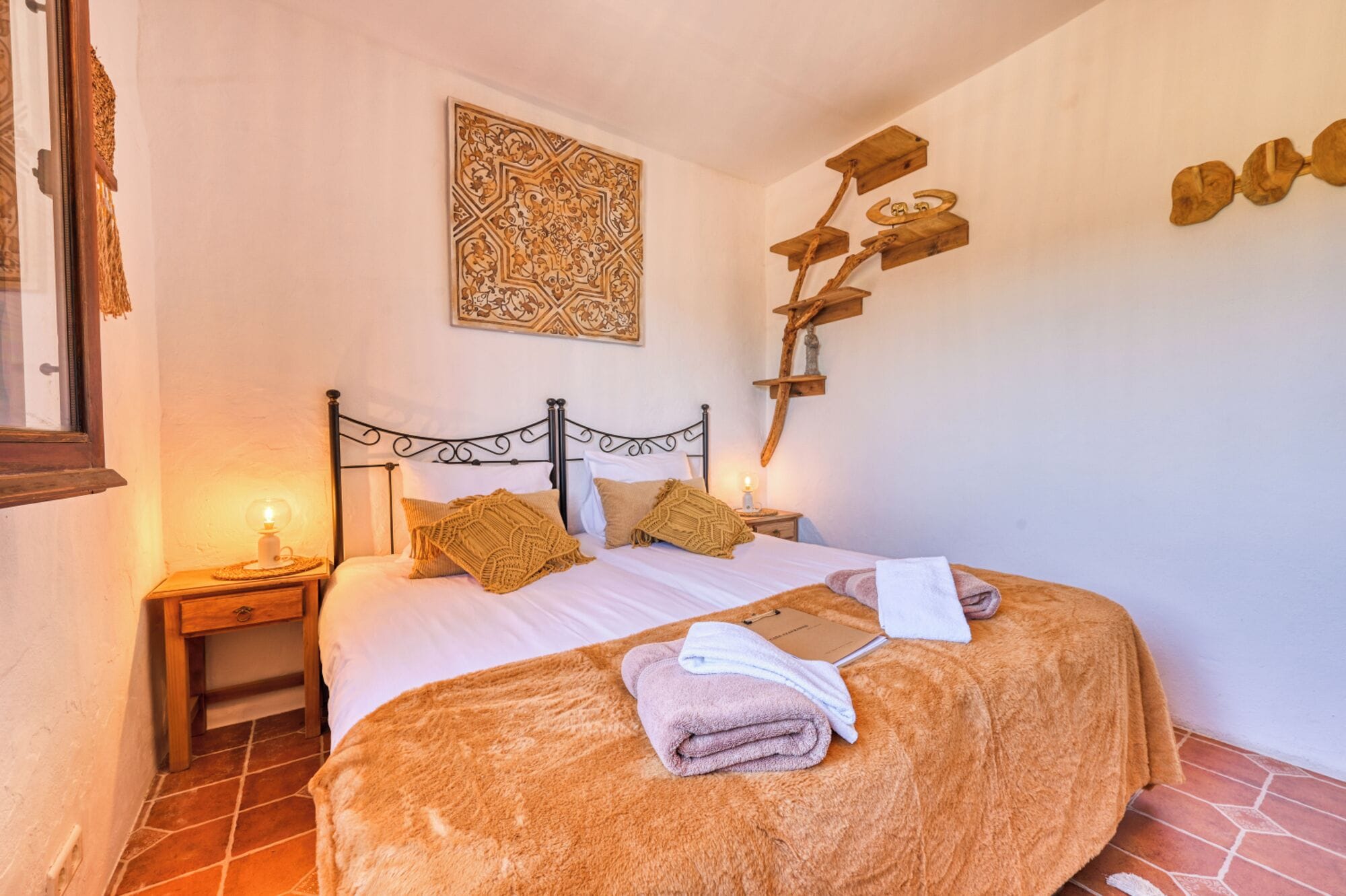 Un dormitorio con una cama, una mesita de noche, un estante en la pared y un adorno mural.