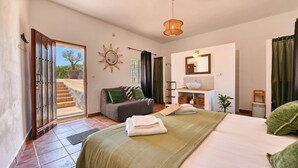 Un dormitorio con cama, escritorio, silla, ventana y puerta que da a un espacio exterior.