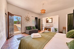 Ein Schlafzimmer mit Bett, Schreibtisch, Stuhl, Fenster und einer Tür zu einem Außenbereich.