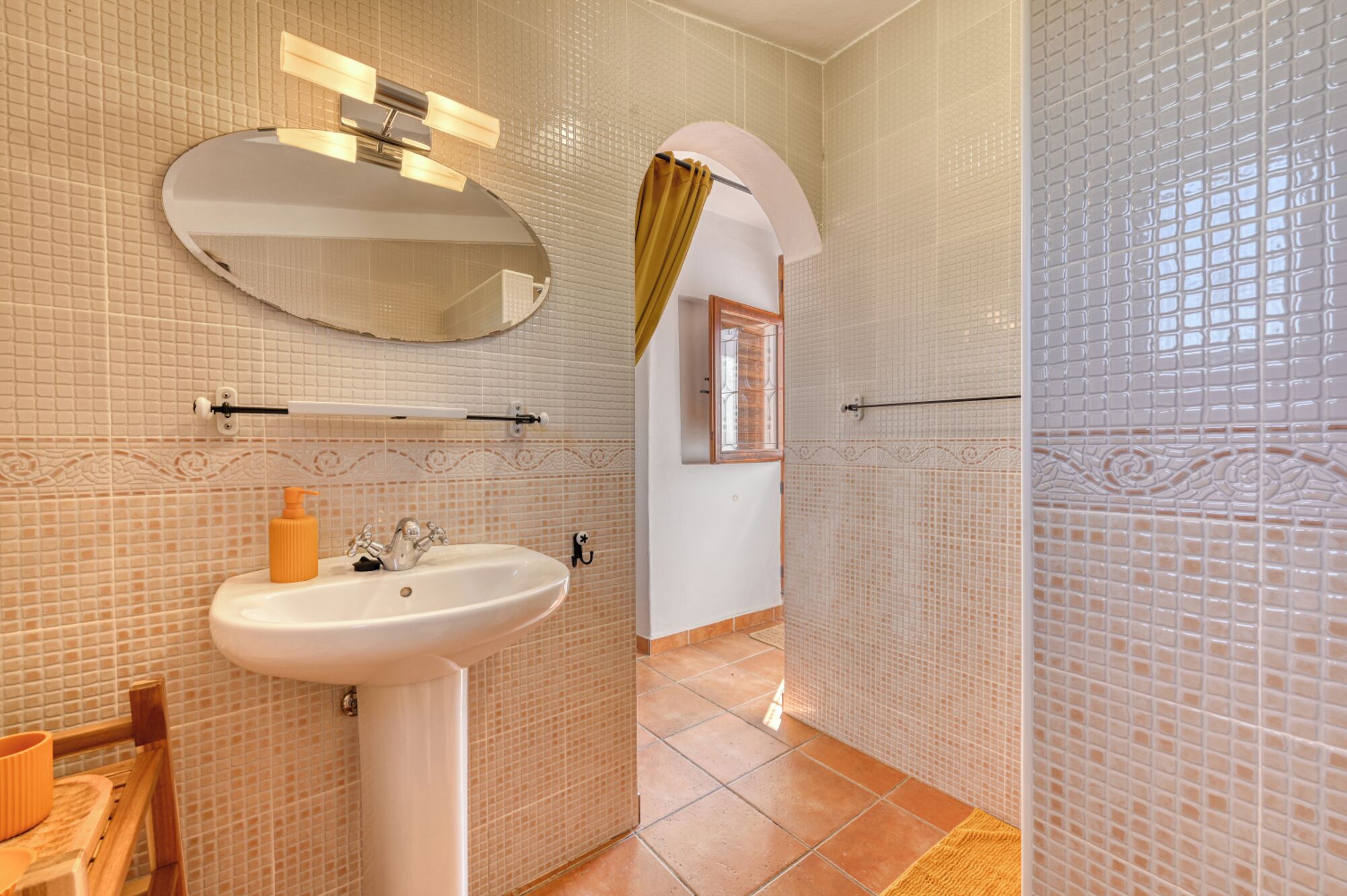 A bathroom with a white sink, mirror, and tiled walls.
