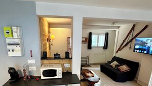 Un espacio habitable compacto con kitchenette, comedor y zona de estar con televisor.